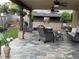 Inviting covered outdoor patio with stone flooring, an outdoor kitchen, and comfortable seating area at 60 Saddle Tree Way, Sugar Hill, GA 30518