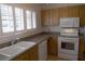 This kitchen features a double basin sink, light wood cabinets, and white appliances at 1932 Variations Ne Dr, Atlanta, GA 30329