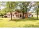 Charming one-story home with red shutters, a covered porch, mature shade trees, and a hammock at 175 Heritage Farm Ln, Fayetteville, GA 30215