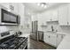 Modern kitchen featuring white cabinets, stainless steel appliances, and mosaic backsplash, with gas range at 63 Fulton Se St, Atlanta, GA 30312