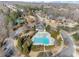 Aerial view showcasing a neighborhood home with a community pool, lush landscaping, and surrounding wooded areas at 6455 Quiet Cove Rd, Cumming, GA 30041