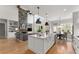 Open-concept kitchen featuring a large island, hardwood floors, stone fireplace and an adjacent living area at 6455 Quiet Cove Rd, Cumming, GA 30041