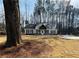 View of the home nestled on a spacious lot with mature trees and a circular driveway at 494 West Ave, Bowdon, GA 30108