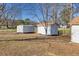 View of various white outbuildings with brown roofs in a fenced backyard setting at 5692 Rock Patch Rd, Loganville, GA 30052