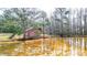 Scenic view of a red home by a pond, surrounded by lush greenery at 257 Crossroads Church Rd, Rockmart, GA 30153