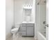 Bright bathroom featuring a toilet, shower-tub combo with white tiling, and a vanity with a mirror and modern lighting at 6145 Stargazer Way, Cumming, GA 30028