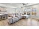 Bright living room features a gray sectional sofa, wood floors, and large windows overlooking the deck at 6145 Stargazer Way, Cumming, GA 30028