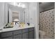 Well-lit bathroom with gray vanity and shower/tub combo featuring a black and white polka dot shower curtain at 3775 Lake Seminole Dr, Buford, GA 30519