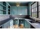 Well-lit laundry room featuring blue cabinets, herringbone backsplash, dark countertop, and gold hardware at 555 Orme Ne Cir, Atlanta, GA 30306