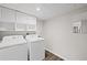 Bright laundry room featuring white washer and dryer set with overhead white cabinets and neutral walls at 1415 Dalewood Ne Dr, Atlanta, GA 30329