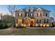 Beautiful two-story home featuring a stone facade, manicured lawn, and charming shuttered windows at twilight at 4440 Croftshire Pl, Cumming, GA 30040