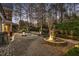 Backyard featuring a large fountain, tranquil pool, stone patio, and lush landscaping, lit for evening enjoyment at 5400 Saint Lyonn Pl, Marietta, GA 30068