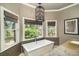 A freestanding white soaking tub is showcased, positioned beneath large windows with natural light at 5400 Saint Lyonn Pl, Marietta, GA 30068