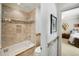 Bathroom featuring a shower-tub with a glass door, neutral tile, and view to a bright bedroom at 5400 Saint Lyonn Pl, Marietta, GA 30068