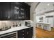 Wet bar area featuring black cabinetry, tile backsplash, and views into the white kitchen at 5400 Saint Lyonn Pl, Marietta, GA 30068