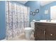 Bright bathroom with blue walls, decorative shower curtain, updated vanity, and modern fixtures at 7158 Georges Way, Morrow, GA 30260