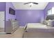 Stylish purple bedroom featuring a modern bed, mirrored dresser, mounted TV, and neutral carpet at 7158 Georges Way, Morrow, GA 30260