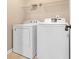 Functional laundry room with white washer and dryer, and overhead shelving for storage at 7158 Georges Way, Morrow, GA 30260