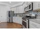 Features a stainless steel refrigerator, range, microwave, and decorative backsplash in this modern gray and stainless kitchen at 1784 Treymire Ct, Stone Mountain, GA 30088