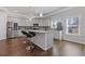 Bright kitchen features stainless steel appliances, gray cabinetry, tile backsplash, granite countertops, and a central island with barstool seating at 1784 Treymire Ct, Stone Mountain, GA 30088