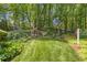 Spacious backyard featuring mature trees, a swing set, and lush greenery, perfect for outdoor recreation and relaxation at 2802 Nettle Ln, Buford, GA 30519