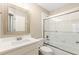 Bathroom with framed mirror, white vanity, and glass-enclosed tiled tub and shower combo at 2802 Nettle Ln, Buford, GA 30519