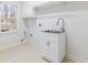 Well-lit laundry room with stainless steel sink, white cabinets, and tile flooring at 2802 Nettle Ln, Buford, GA 30519