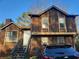 Two-story home with brown wooden exterior, stairs leading to the front door, and a black car parked in front at 1085 Mainstreet Valley Dr, Stone Mountain, GA 30088