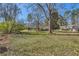 Large grassy backyard with mature trees and residential homes in the distance at 3045 Riviera Nw Dr, Conyers, GA 30012