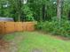View of a grassy backyard enclosed by a wooden fence and mature trees, providing privacy at 401 Peggy Ln, Villa Rica, GA 30180