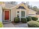 Close up of home's entrance featuring a red door, black awning, and manicured bushes at 7238 Hummingbird Ln, Winston, GA 30187