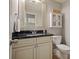 Elegant bathroom with a granite countertop, decorative mirror, and classic white cabinetry at 3003 Maple Ln, Alpharetta, GA 30009