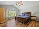 Spacious bedroom featuring wood floors, ceiling fan, and a large window offering abundant natural light at 3003 Maple Ln, Alpharetta, GA 30009