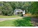 Inviting two-story home with a charming front porch, set against a backdrop of mature trees and a well-kept lawn at 3003 Maple Ln, Alpharetta, GA 30009