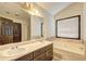 Bright bathroom featuring double sinks, vanity, tub, and a large window for natural light at 375 Tambec Nw Trce, Lilburn, GA 30047
