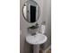 Modern powder room featuring a pedestal sink, round mirror, and modern fixtures at 4212 Logan Dr, Loganville, GA 30052