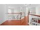 Upstairs hallway with hardwood floors, white railing, and a large window providing natural light at 2283 Shady Maple Ln, Loganville, GA 30052