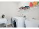 Bright laundry room featuring white washer, dryer, utility sink, and shelving for organized storage at 2283 Shady Maple Ln, Loganville, GA 30052