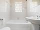 Bathroom features a bathtub, tiled walls, and a window made of glass blocks at 3542 W Hill St, Clarkston, GA 30021