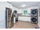 Modern kitchen featuring white cabinetry, stainless steel appliances, and a stacked washer/dryer at 2598 Elliott Nw St, Atlanta, GA 30318
