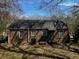 View of a brick house backyard with overgrown plants and a dark shadow at 2319 Browns Mill Se Rd, Atlanta, GA 30315