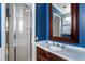 Modern bathroom showcasing a glass shower, a marble countertop vanity, and a framed mirror against blue walls at 189 Westminster Dr, Atlanta, GA 30309