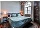 Bedroom featuring a comfortable bed, exposed brick accent wall, and large window overlooking the city at 3180 Mathieson Ne Dr # 806, Atlanta, GA 30305