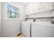 Bright laundry room featuring a side-by-side white washer and dryer and storage cabinets at 4240 Parnell Rd, Marietta, GA 30062