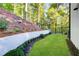 Well-maintained backyard with green lawn, retaining wall with landscaping, and fenced perimeter at 6090 River Chase Cir, Atlanta, GA 30328