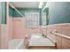Classic bathroom with pink tile, a tub, a toilet, and a sink with a white countertop at , Atlanta, GA 30329