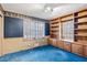 Bedroom with bright blue carpet, built-in shelving, and a window with wooden blinds for natural light at , Atlanta, GA 30329