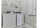 Laundry room with washer, dryer, wire rack shelf, and tile flooring at 301 Cochin Dr, Woodstock, GA 30188