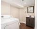 Functional laundry area with a washer/dryer, vanity sink, and dark wood-look flooring at 5498 Stoneybrook Se Ct, Mableton, GA 30126