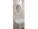 White pedestal sink with oval mirror and modern lighting fixture in a well-lit bathroom at 3287 Belmont Glen Se Dr, Marietta, GA 30067